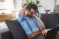 Smiling young businessman working on laptop computer while sitting on sofa at home Royalty Free Stock Photo