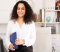 Young businesswoman with clipboard politely welcoming to company office