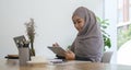 Smiling young businesswoman in hijab working in bright modern office and using modern devices Royalty Free Stock Photo