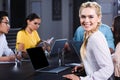 smiling young businesswoman looking at camera while her colleagues working behind at modern Royalty Free Stock Photo