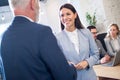 Smiling young businesswoman shaking hands with senior businessman in office. Royalty Free Stock Photo