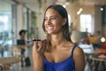 Smiling Young Businesswoman Standing In Busy Office Talking Into Mic Of Mobile Phone Royalty Free Stock Photo