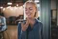 Smiling young businesswoman talking on speakerphone in an office