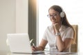 Smiling young businesswoman wearing headphones looking at pc lap Royalty Free Stock Photo