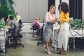 Smiling young businesswomen using smartphone and talking while colleagues working behind Royalty Free Stock Photo