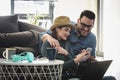 Smiling young Caucasian couple shopping online at home using a laptop with a credit card Royalty Free Stock Photo