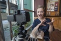 Smiling young caucasian girl woman making a video blog vlog with camera in a cafe