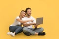 Smiling young caucasian lady hugging guy in white t-shirts show on computer, sit on floor Royalty Free Stock Photo