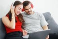 Smiling young Caucasian lover Couple listening to online music with Headphones and laptop together in living room. Lifestyle and Royalty Free Stock Photo