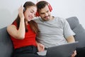 Smiling young Caucasian lover Couple listening to online music with Headphones and laptop together in living room. Lifestyle Royalty Free Stock Photo