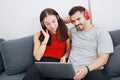 Smiling young Caucasian lover Couple relish for listening to online music with Headphones and laptop together in living room. Royalty Free Stock Photo