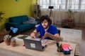 Smiling young Caucasian male employee in headphones work distant on laptop at home office thinking dreaming. Happy Royalty Free Stock Photo