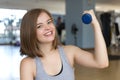 Smiling young caucasian woman girl doing workout with light dumbbells at the gym, lifting weights Royalty Free Stock Photo