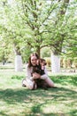 Smiling young Caucasian woman is hugging her puppy of chocolate Labrador retriever dog on a walk in summer park Royalty Free Stock Photo