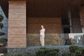 Smiling young caucasian woman talking on mobile phone standing outdoors with coffee, wearing elegant attire looking away with Royalty Free Stock Photo