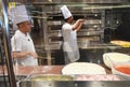 Smiling young chef in a white uniform serves traditional Italian pizza on a cruise liner MSC Meraviglia. 10 October 2018 Royalty Free Stock Photo