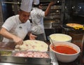 Smiling young chef in a white uniform serves traditional Italian pizza on a cruise liner MSC Meraviglia. 10 October 2018 Royalty Free Stock Photo