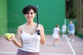 Smiling young Chilean woman with racket and balls on outdoor frontenis court Royalty Free Stock Photo