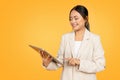 Smiling young chinese businesswoman in suit, typing on tablet, chatting