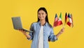 Smiling young chinese female student with many different flags and laptop Royalty Free Stock Photo
