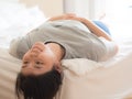 Smiling young chinese woman lying upside down on the bed Royalty Free Stock Photo