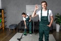 smiling young cleaning company workers using vacuum cleaner and showing ok sign Royalty Free Stock Photo