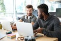 Smiling young colleagues sitting in office coworking using laptop Royalty Free Stock Photo