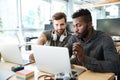 Smiling young colleagues sitting in office coworking using laptop Royalty Free Stock Photo