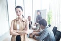 Smiling young confident Asian businesswoman at office with her mixed race colleagues in background, start up business and Royalty Free Stock Photo