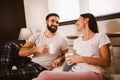 Young couple in bed drinking coffee and looking each other Royalty Free Stock Photo