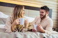 Young couple dressed in bathrobes lying on bed and drinking coffee Royalty Free Stock Photo