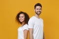 Smiling young couple friends european guy african american girl in white t-shirts posing isolated on yellow background Royalty Free Stock Photo