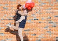 Smiling young couple holding hands standing in front of brick wall Royalty Free Stock Photo