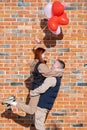 Smiling young couple holding hands standing in front of brick wall Royalty Free Stock Photo