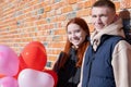 Smiling young couple holding hands standing in front of brick wall Royalty Free Stock Photo