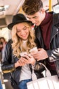smiling young couple in leather jackets using smartphone in public
