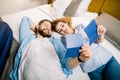Smiling young couple looking at their passports for travel, while lying on the bed in hotel or appartment room Royalty Free Stock Photo