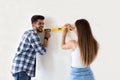 Smiling young couple measuring wall with level tool, renovation Royalty Free Stock Photo