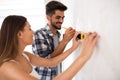 Smiling young couple measuring wall with level tool, renovation Royalty Free Stock Photo