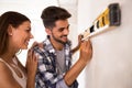 Smiling young couple measuring wall with level tool, renovation Royalty Free Stock Photo