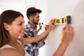 Smiling young couple measuring wall with level tool, renovation Royalty Free Stock Photo