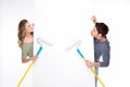 Smiling young couple with paint rollers and blank card looking at each other Royalty Free Stock Photo