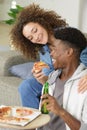 Smiling young couple with pizza on sofa at home Royalty Free Stock Photo