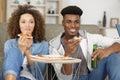 smiling young couple with pizza on sofa at home Royalty Free Stock Photo