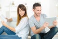 Smiling young couple reading ebooks on sofa at home
