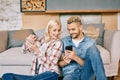Smiling young couple relaxing on couch with smartphone at home Royalty Free Stock Photo