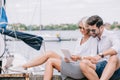 smiling young couple in sunglasses sitting and using digital tablet Royalty Free Stock Photo