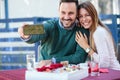 Smiling young couple taking a selfie in an outdoor cafe