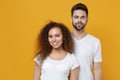 Smiling young couple two friends european guy african american girl in white t-shirts posing isolated on yellow wall Royalty Free Stock Photo