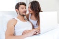 Smiling young couple using laptop in bed Royalty Free Stock Photo